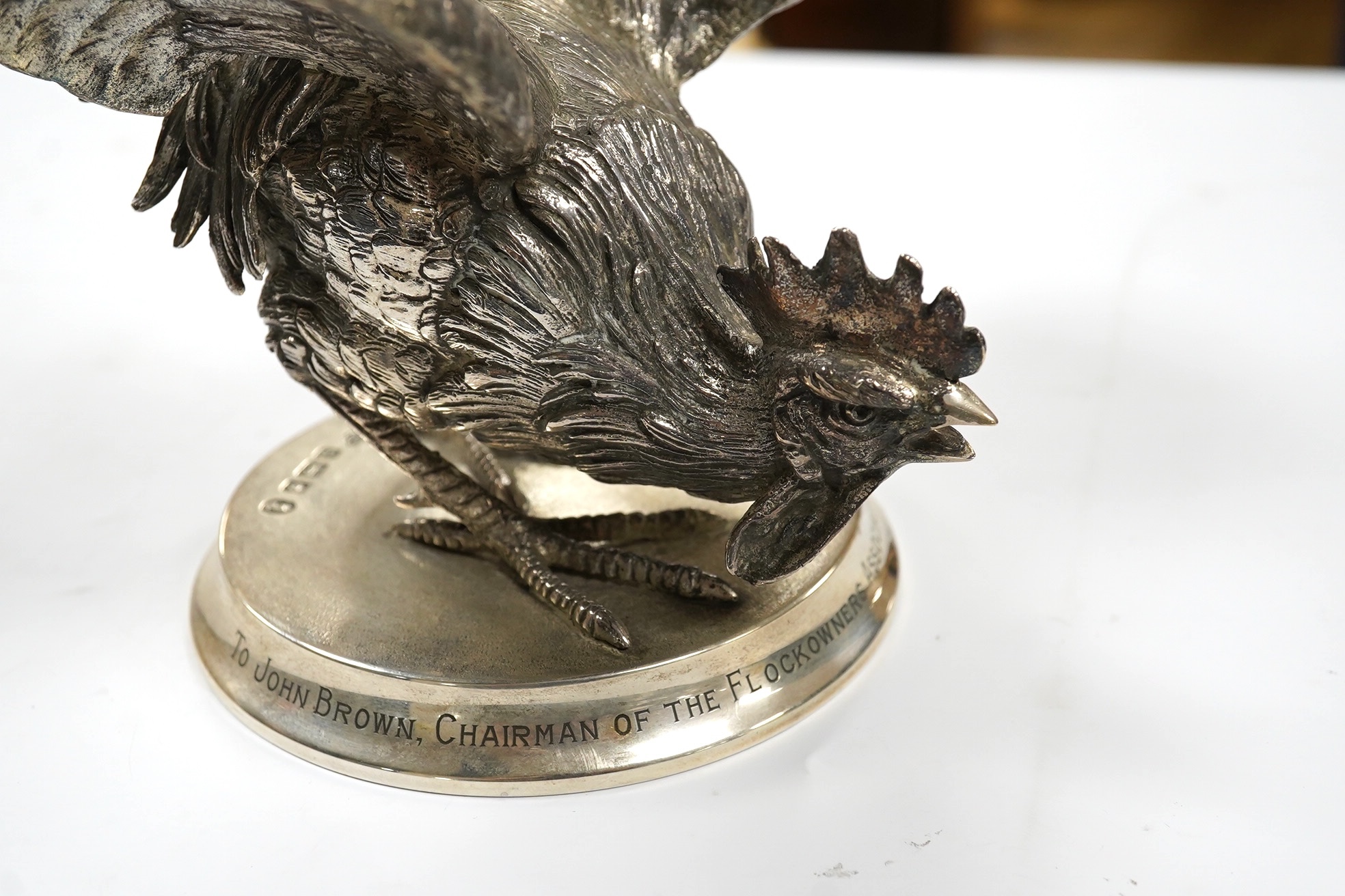 An Elizabeth II silver presentation cockerel, on a circular base with engraved inscription, by Garrard & Co Ltd, London, 1953, overall height 14cm, weighted. Condition - fair to good